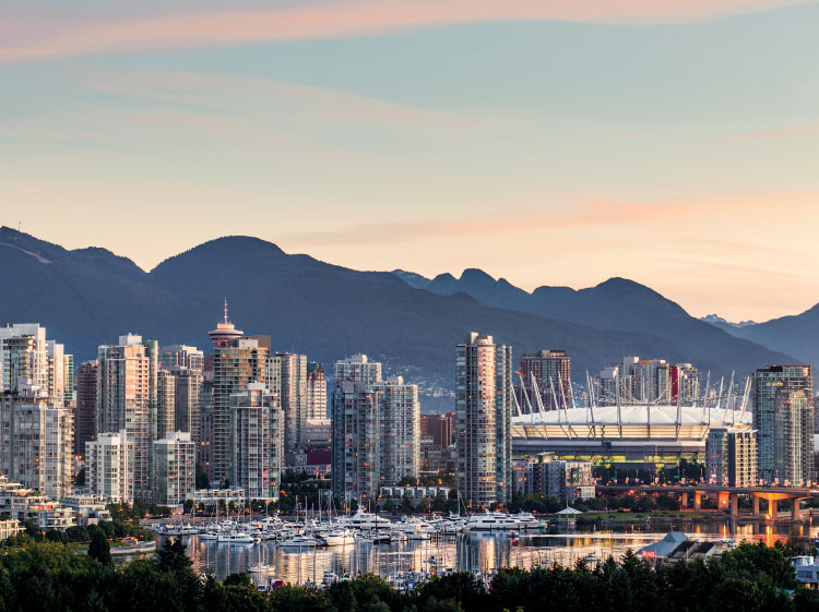 Aerial view of Downtown Vancouver BC at sunset with snow capped mountains in the distance